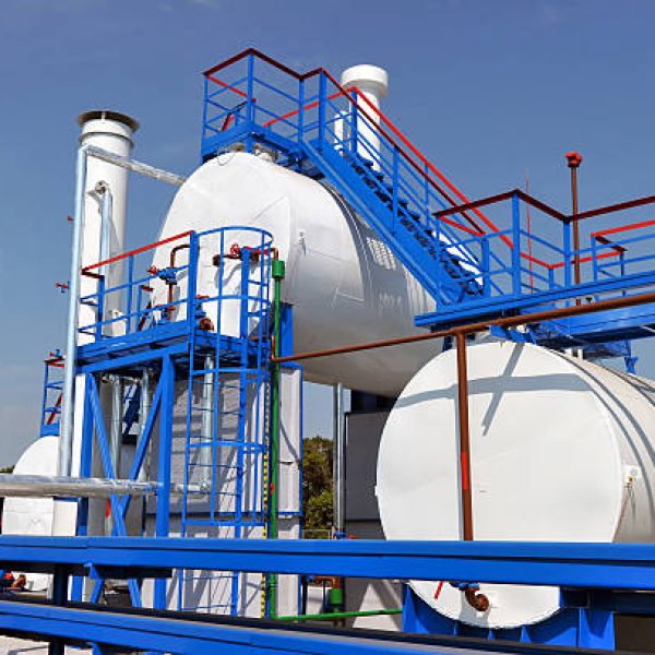 White fuel tanks and color gas pipes in natural gas treatment plant in bright sunny summer day